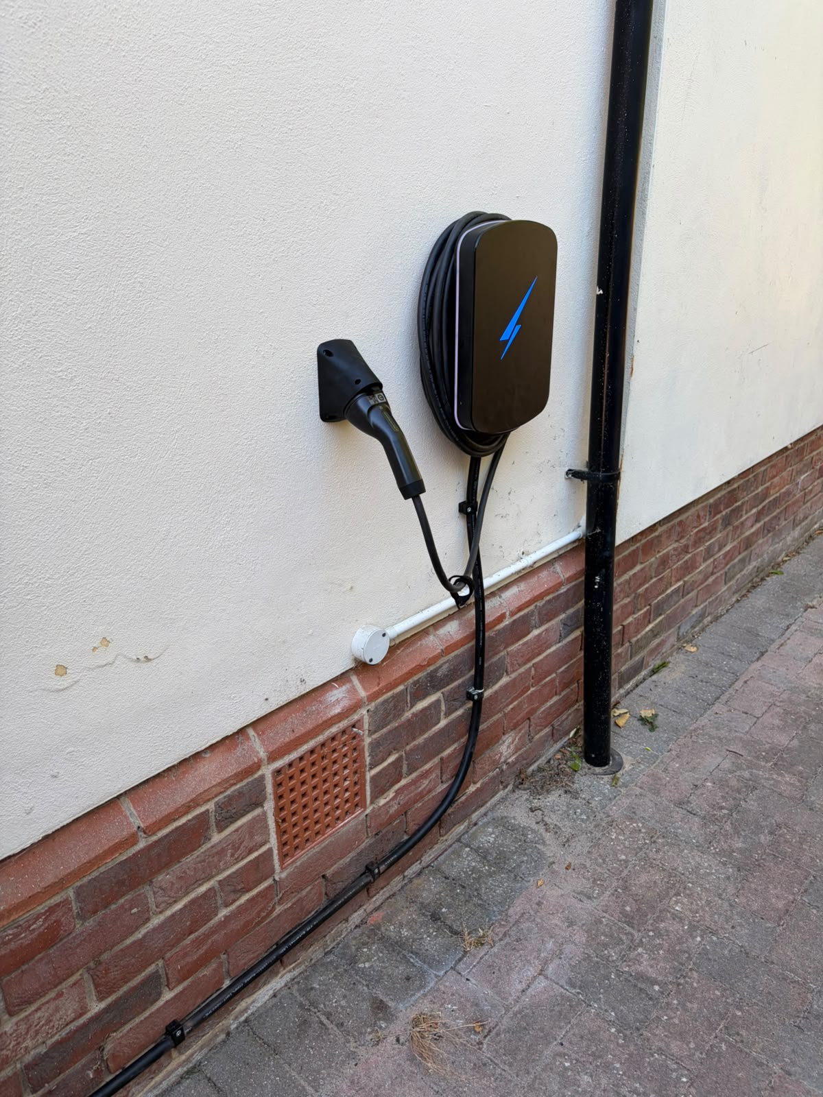 Tethered EV charge point installed on a rendered house wall with neat cable containment